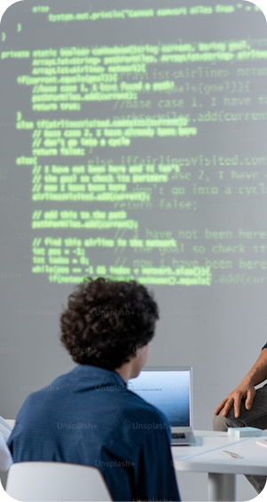 A man seated in front of a computer with code